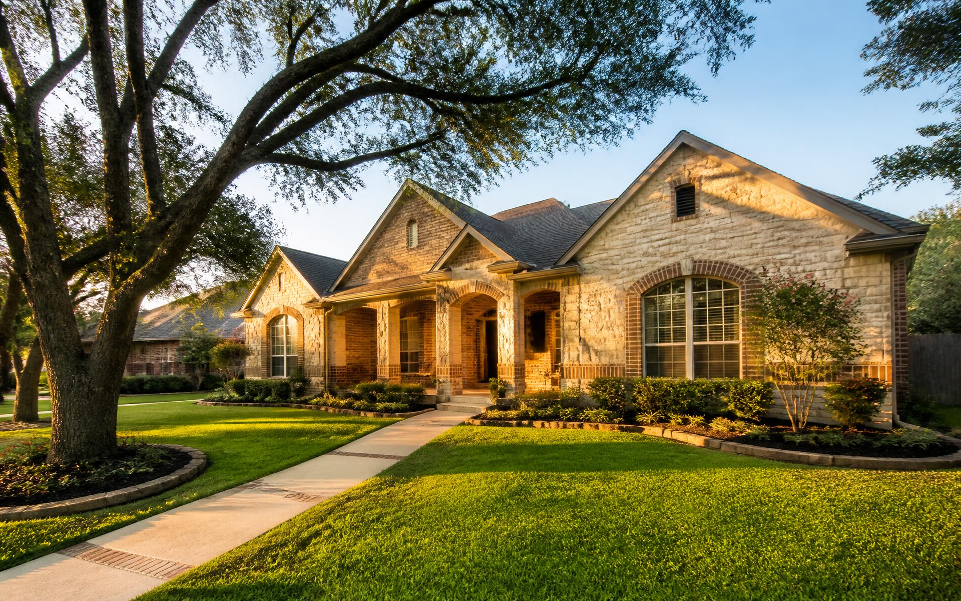 Warm Texas home with mature oak trees at golden hour